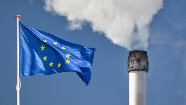 Bremsen beim Klimaschutz Eine EU-Fahne weht vor einem Fabriksschlot, der Rauch ausstößt