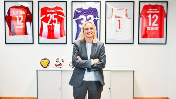 Staatssekretärin Michaela Schmidt und Regierungskoordinatorin steht vor einer Wand mit Sporttrikots