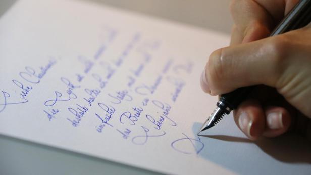Eine Hand mit Füllfeder schreibt einen Brief