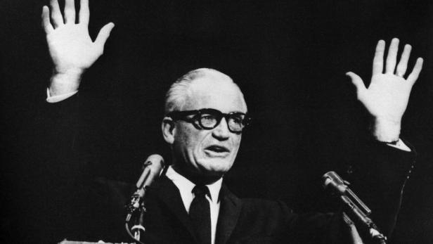 Schwarzweißfoto von Goldwater mit erhobenen Händen bei einer Rede