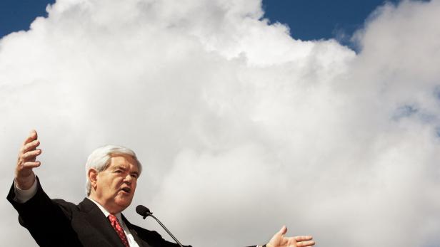 Ein Mann steht mit weit ausgebreiteten Armen vor einem Hintergrund mit Himmel und Wolken