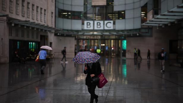 Mitarbeiter mit Regenschirmen vor dem Eingang der BBC-Redaktion 