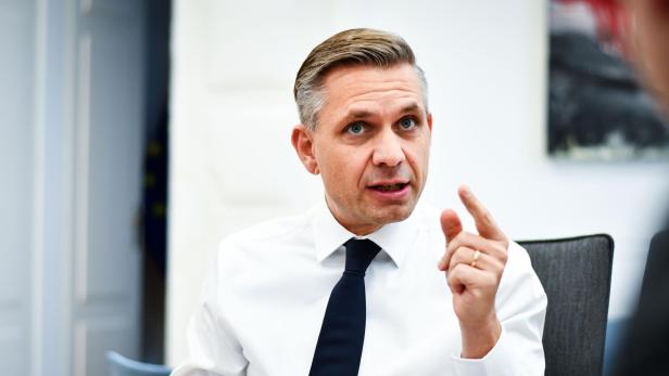 zu sehen ist der ÖVP-Wirtschaftsminister Wolfgang Hattmannsdorfer in einer Interviewsituation, er trägt ein weißes Hemd und Krawatte