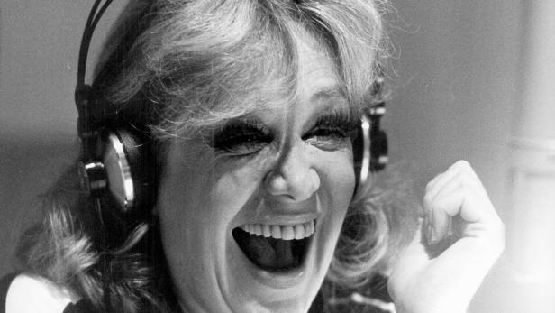 Hildegard Knef, lachend, mit Kopfhörern übergestülpt.