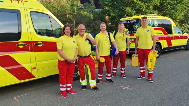 Mehrere Rettungssanitäter stehen vor einem Rettungswagen.