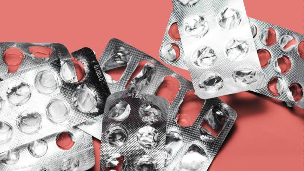Leere Medikamente-Durchdrückpackungen liegen verstreut auf einem roten Hintergrund
