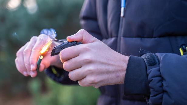 zu sehen ist ein Feuerwerkskörper, der in der Hand gezündet wird