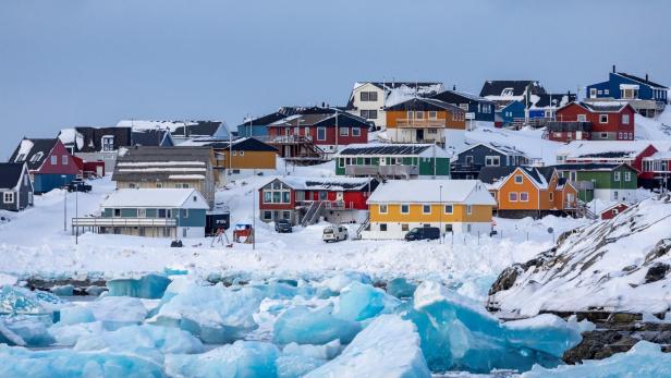 Im Vordergrund ist Eis zu sehen, im Hintergrund farbige Häuser der grönländischen Hauptstadt Nuuk.