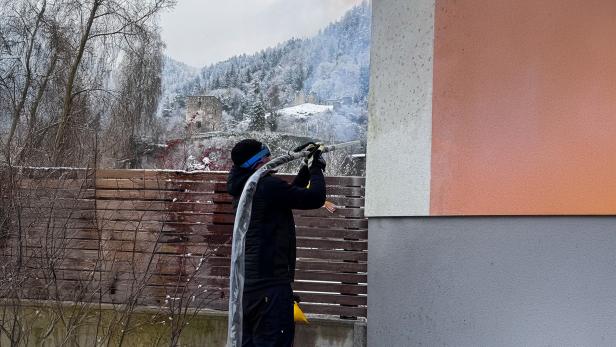 Person reinigt eine Hausfassade im Winter mit einem Trockeneisstrahlgerät.