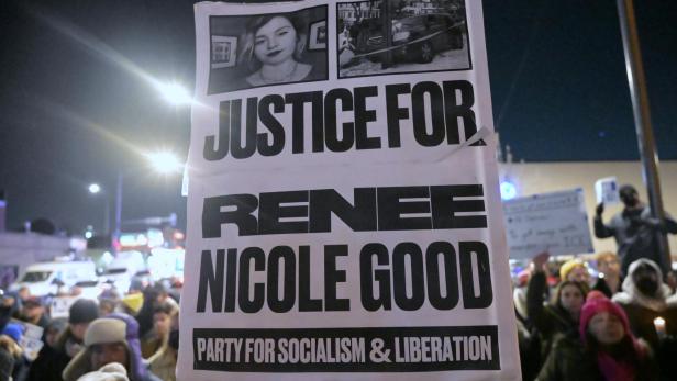 Auf einem Plakat steht: "Gerechtigkeit für Renee Nicole Good" in English, im Hintergrund sind Demonstrierende zu sehen.