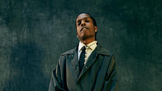Rapper Asap Rocky posiert in grauem Anzug vor grauem Hintergrund