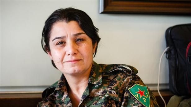 Nesrin Abdullah in Tarnkleidung, sie trägt am Arm einen Aufnäher mit der Aufschrift "YPJ" und einem roten Stern.