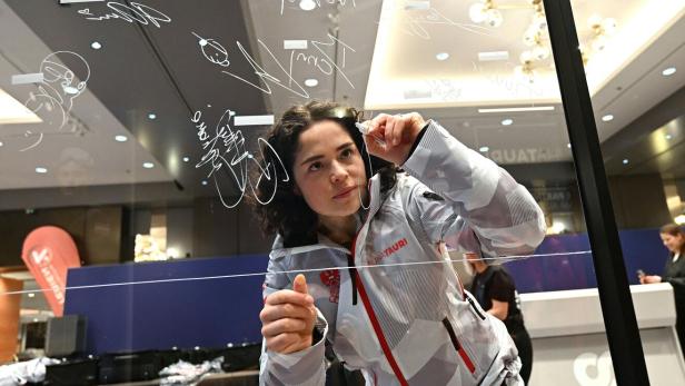 Die Skirennfahrerin Julia Scheib schreibt ihr Autogramm auf eine transparente Scheibe