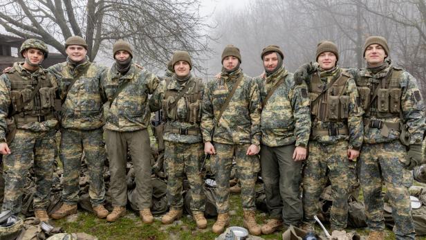Acht Rekruten in Uniform posieren auf dem Truppenübungsplatz
