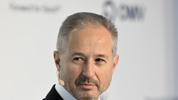 Alfred Stern, OMV-Chef, steht im Anzug mit Mikrofon vor einem Hintergrund mit OMV-Logo und blickt zur Seite.