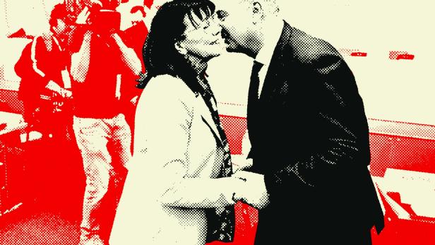 Walter Ruck begrüßt eine Frau herzlich, während im Hintergrund Kamerateams die Szene dokumentieren.