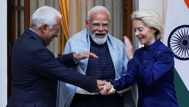 Eu-Kommissions Präsidentin von der Leyen (rechts) und Europäischer Rats Präsident António Costa (links) schütteln die Hände von Indiens Premier Narendra Modi (Mitte). Im Hintergrund rechts ist eine indische Fahne zu sehen.