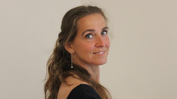 Eine Frau in einem schwarzen Oberteil, schaut über ihre Schulter 