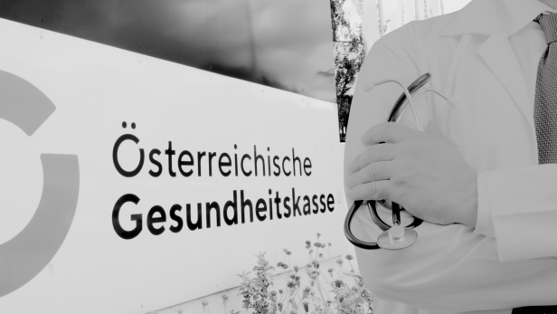 Ein Arzt steht vor dem Schild der ÖGK