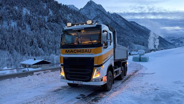 Lastwagen der MACHBAU GmbH auf verschneiter Straße vor winterlicher Bergkulisse in Osttirol.