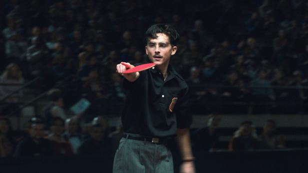 Timothée Chalamet mit Tischtennisschläger in einem abgedunkelten Raum