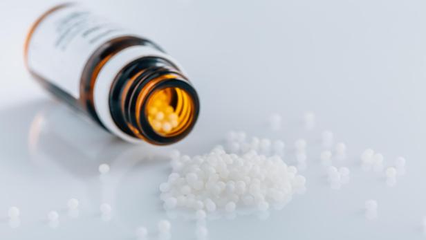 Ein Glasfläschchen, das homöopathische Globuli beinhaltet.