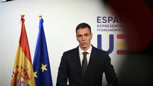 Pedro Sánchez steht vor einer Spanien- und EU-Flagge.