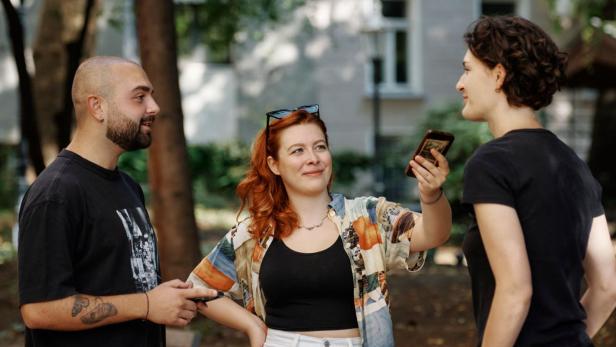 Ein Mann und eine Frau interviewen in einem Parkgelände eine weitere Person