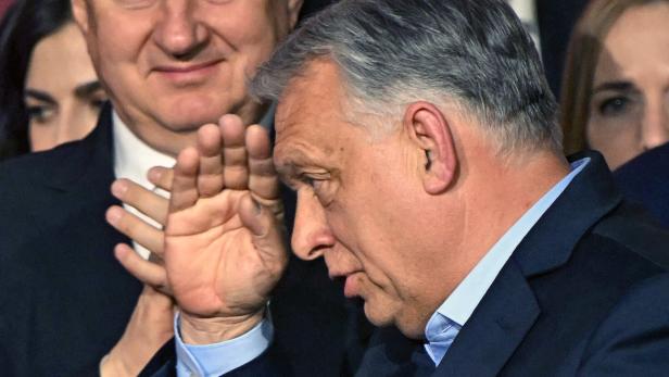 Ein Mann, Viktor Orban, salutiert. Im Hintergrund stehen Menschen.