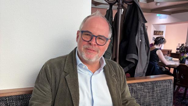 Hotelier Wolfgang Gröller sitzt an einem Wirtshaustisch, vor sich ein Kupferkessel und ein Teller mit Kartoffelpüree