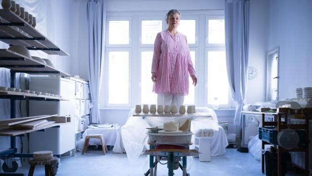 Die Künstlerin Uli Aigner steht in ihrem Studio auf einem Hocker