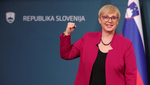 Eine Frau reckt vor der Flagge Sloweniens die Faust