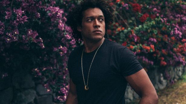 Der US-Musiker Makaya McCraven vor einer blühenden Staude