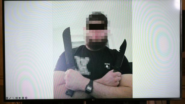Mann mit verpixeltem Gesicht hält zwei große Messer vor weißem Hintergrund gekreuzt in den Händen.