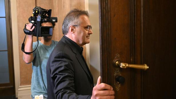 Der Ex-BVT-Beamte Egisto geht durch eine Tür am Wiener Straflandesgericht. Dahinter steht ein Kameramann.