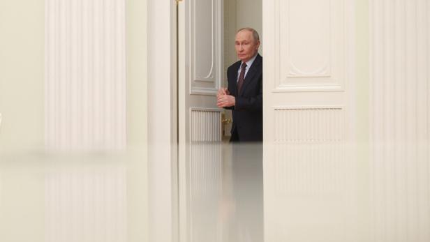 Putin betritt einen Raum durch eine weiße Tür
