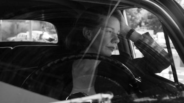Schwarzweißes Bild der Schauspielerin Sandra Hülle, die in einem Auto sitzt und versunken nach draußen blickt