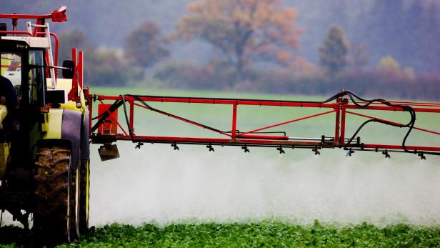 Ein Landwirt versprüht ein Pflanzenschutzmittel auf einem Feld. 