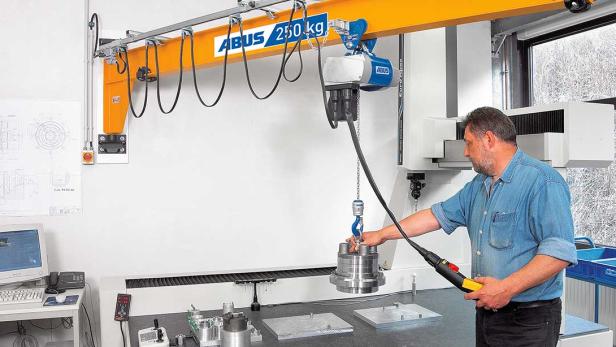 Mitarbeiter bedient einen ABUS-Schwenkkran und hebt ein Metallteil in einer Werkstatt.