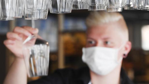 Barkeeper mit Maske hinter Weinkläsern