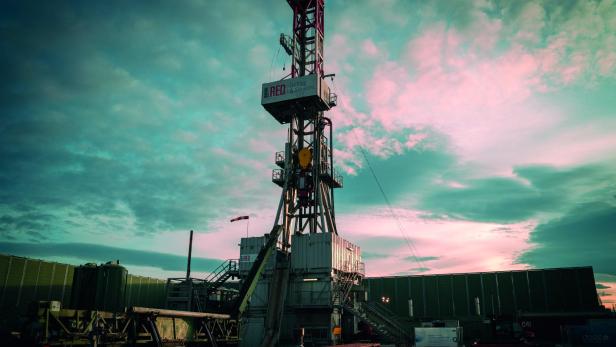Bohrturm auf einer Baustelle vor bewölktem Himmel bei Sonnenuntergang