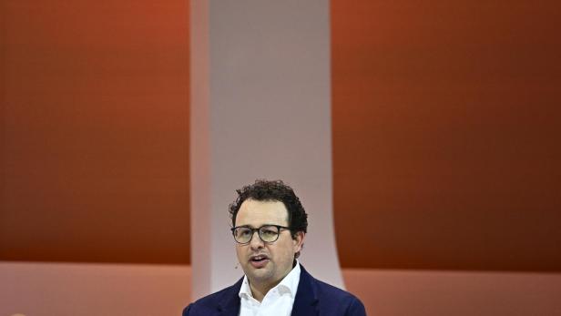 Dario Amodei spricht auf einer Bühne vor orangefarbenem Hintergrund.