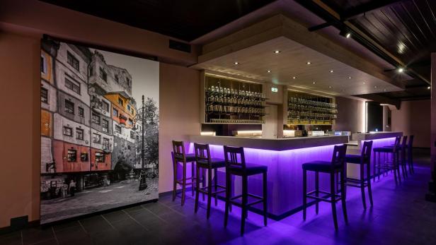 Leere Bar mit violett beleuchtetem Tresen in moderner Eventlocation.