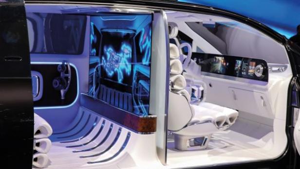 Innenraum eines futuristischen Fahrzeugs mit weißen Sitzen, großem digitalem Display und blauer Ambientebeleuchtung