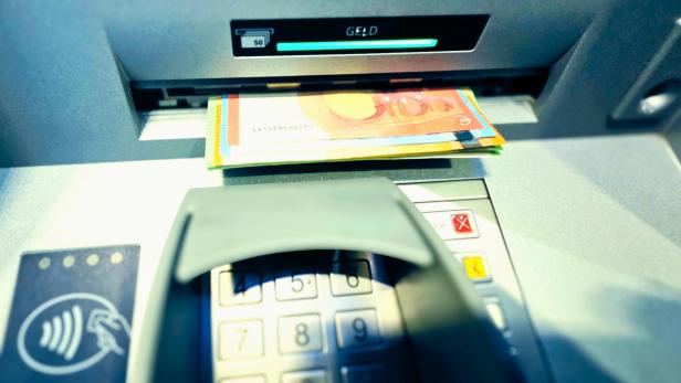 Bargeld am Bankomatenschlitz über der Tastatur, Nahaufnahme