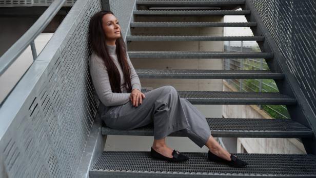 Frau sitzt auf einer Metalltreppe.
