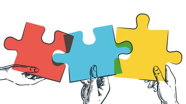 3 Hände halten 3 Puzzleteile hoch