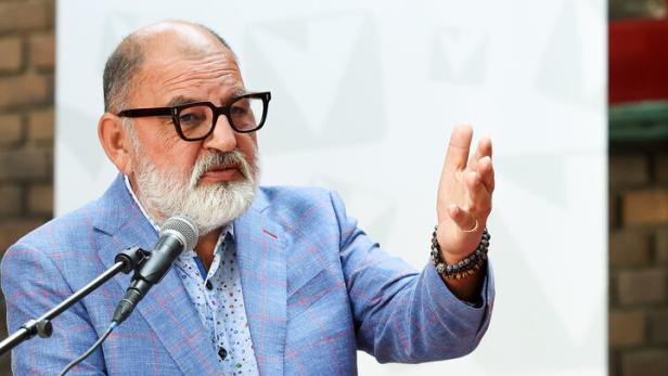 Herbert Schweiger vor einem Plakat der Volkshochschulen