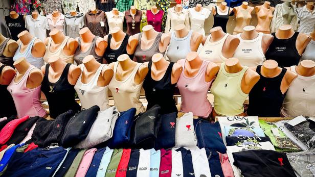 Gefälschte Markenkleidung liegt aufgereiht auf einem Marktstand in der Excalibur City