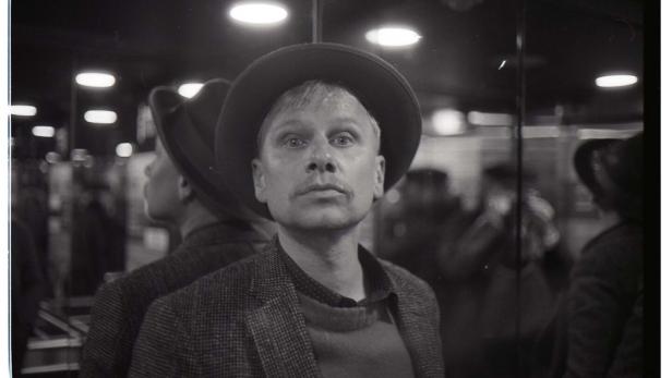 Der Schauspieler und Musiker Robert Stadlober mit Hut und erstauntem Blick in einem schwarzweißen Bild 